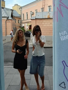 Dettaglio di una camicetta bianca in pizzo con scollo a V e abito nero in stile street