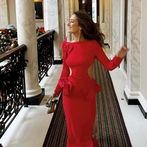 Détail d'une robe de soirée rouge à manches longues avec découpes et grands nœuds