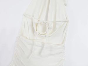 Detailed view of white backless dress featuring elegant ruched sides and cross tie straps