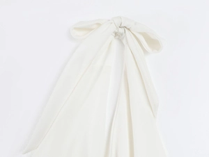 Detail of white knit bow with ribbed texture and pearl accents for slim fit summer dresses
