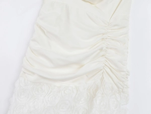 Detailed view of white mini dress featuring side ruching and 3D rose flower hem texture