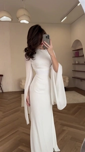 Close-up of elegant white long-sleeve evening gown with draped split sleeves and slim waist