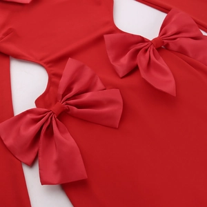 Détail de robe rouge montrant des découpes latérales et des nœuds 3D décoratifs