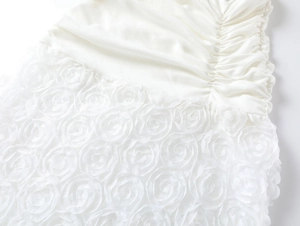Close-up of white summer dress featuring 3D rose appliques and textured ruching details
