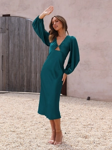 Detail of elegant dark green satin dress featuring a deep V-neck and lantern sleeves