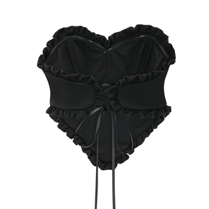 Détail d'un corset noir en forme de cœur avec bordures à volants et laçage au dos