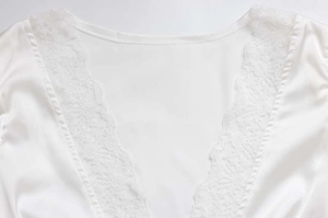 Dettaglio dell'abito in seta bianca con pizzo floreale delicato sullo scollo a V profondo
