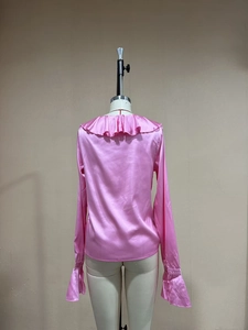 Vista posteriore di un abito in raso rosa con eleganti volant e maniche lunghe a campana