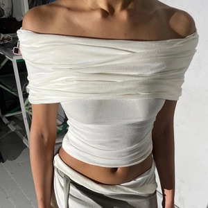 Détail du haut blanc à épaules dénudées montrant la texture plissée et le tissu élastique