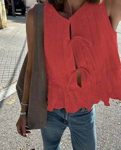 Detail of red sleeveless linen top featuring front bow ties and vertical pleated texture