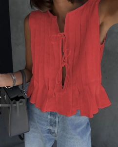 Detailed macro of red pleated sleeveless top featuring front ties and ruffled hemline
