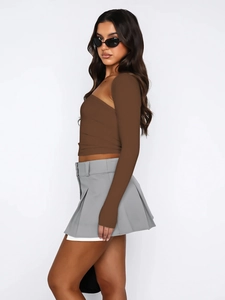 Detail of coffee brown one-shoulder long sleeve top paired with grey pleated skirt