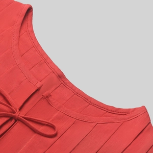 Detail of red sleeveless linen top showing pleated texture and drawstring neckline