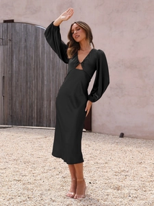 Detailed macro view of the elegant black satin dress with deep V-neck and puff sleeves