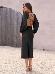 Detail of elegant black satin dress featuring sexy open back with cross-tie ribbon design