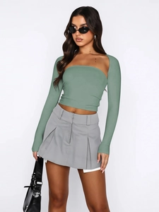 Detail of sage green long-sleeve tube top set with grey pleated mini skirt and handbag