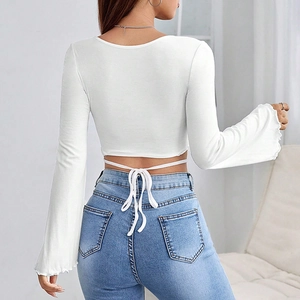 Detail of white crop top featuring elegant flare sleeves and adjustable waist tie back