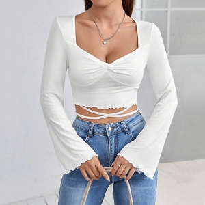Detail view of white square neck crop top featuring waist tie straps and raw hem edge