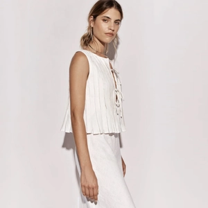 Detail of white linen blend sleeveless top featuring pleated texture and bow tie closures