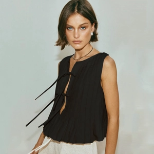 Detail of elegant black pleated sleeveless top with bow-tie front fasteners