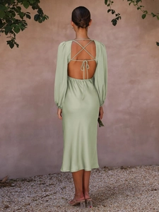 Detail of sage green satin midi dress featuring a deep open back and crisscross tie straps