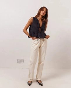 Detail of black pleated sleeveless linen top with V-neck and delicate front tie-up knot