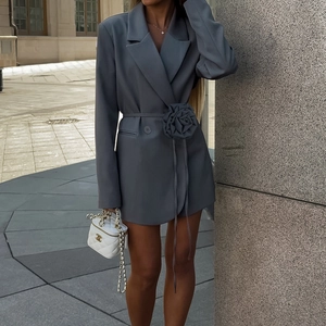 Detail of grey blazer dress featuring a large 3D fabric flower and waist button closure