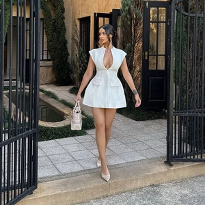 Dettaglio dell'abito corto bianco con scollo a V profondo e tasche decorative a patta