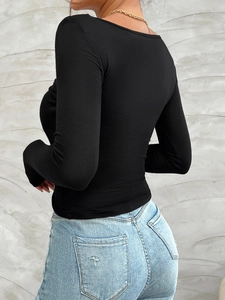 Close-up of a black slim-fit long-sleeve top showing soft fabric and neckline detail