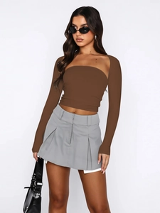 Detail of off-shoulder long sleeve top paired with a gray pleated mini skirt ensemble