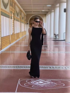 Robe longue moulante noire à une épaule pour femme dans un couloir à colonnes chic