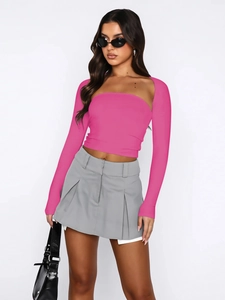 Detail view of the rose pink slim fit strapless top paired with a grey pleated mini skirt