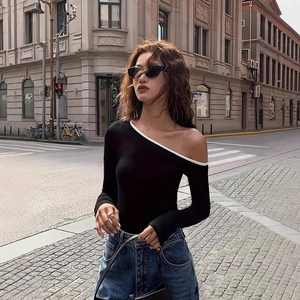 Detail of black off-shoulder top featuring asymmetric neckline and white contrast trim