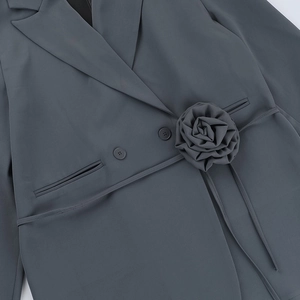 Detailed close-up of dark grey blazer featuring 3D fabric flower and slender waist tie