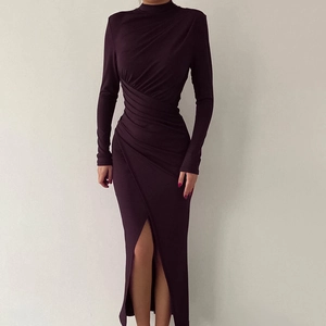 Detail of the high slit and elegant side ruching on a deep purple turtleneck dress