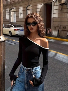 Women's trendy black off-shoulder long sleeve knit top with white trim and denim jeans