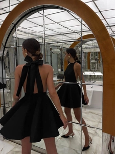 Detail of backless black halter dress featuring a large bow and elegant A-line silhouette