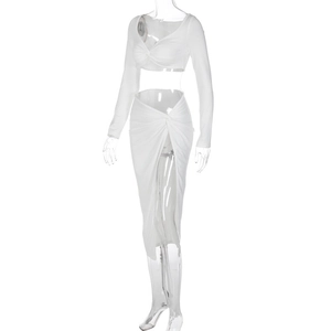 Close-up of white two-piece set featuring V-neck twist crop top and high slit skirt detail