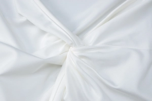 Close-up of elegant twist knot detail and pleated texture on white long sleeve top