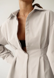 Vue détaillée d'une robe beige à manches longues avec col à revers et plis à la taille