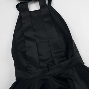 Detail view of the sleek satin fabric and invisible back zipper on this black halter dress