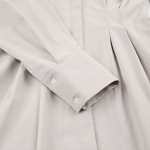 Détails des poignets à double bouton et plis sur la robe grise à manches longues
