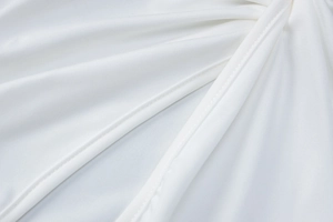 Detailed close-up of premium white knit fabric showing fine double-needle stitching quality