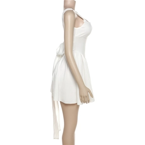 Détail d'une robe courte blanche avec un grand nœud et une jupe plissée sur un mannequin