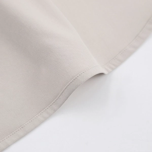 Détail de l'ourlet d'une robe trapèze beige montrant le sergé fin et les coutures nettes