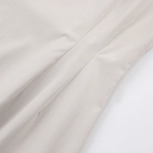 Gros plan sur le tissu beige de la robe trapèze montrant texture et coutures fines
