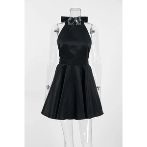 Detail of a black halter mini dress with a large satin bow on the back and pleated skirt