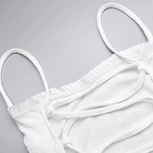 Detail of white spaghetti strap top with floral jacquard texture and ruffled edges