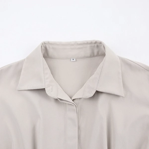 Détail du col classique et patte de boutonnage épurée beige avec étiquette de taille M