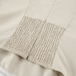 Detail view of smocking design and invisible zipper on khaki cotton linen dress